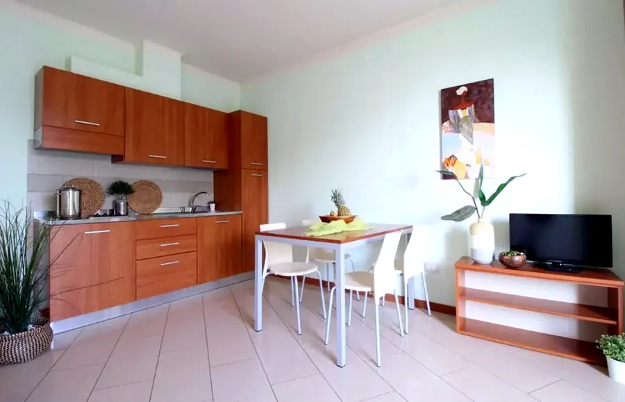 Cucina attrezzata di un appartamento Altamarea con tavolo da pranzo e luce naturale